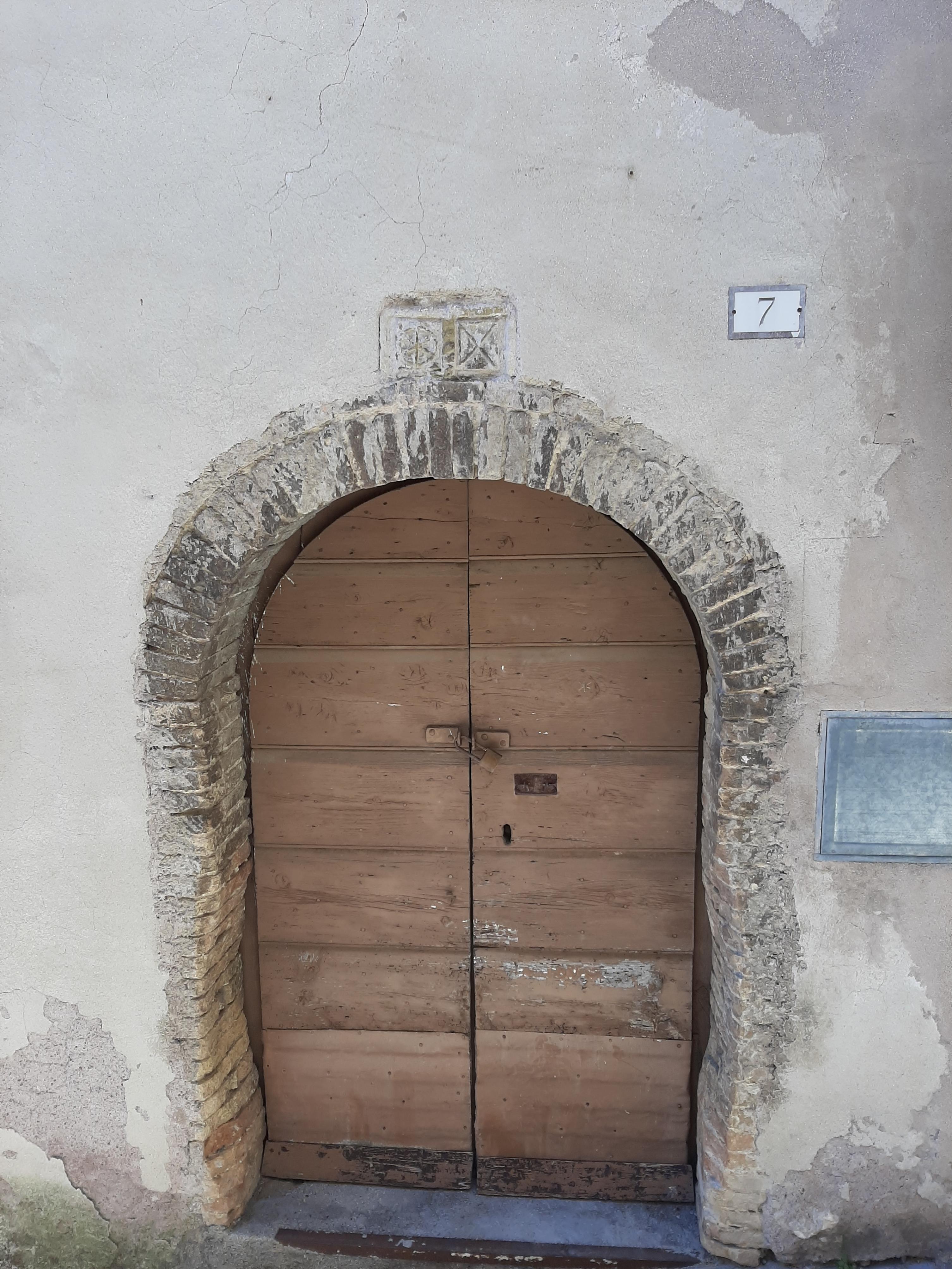 La foto riproduce la mattonella col simbolo difficilmente decifrabile inserito sopra il portone di ingresso di una casa.